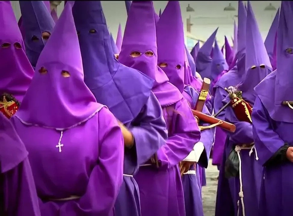 Primer plano de una multitud de capirotes morados apretados en la procesión