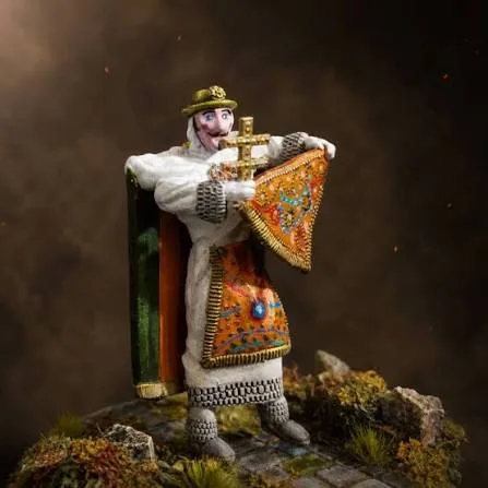 Figura artesanal detallada de un danzante con su cruz y sus pañolones, sobre una base de musgo y con luz cálida de estudio