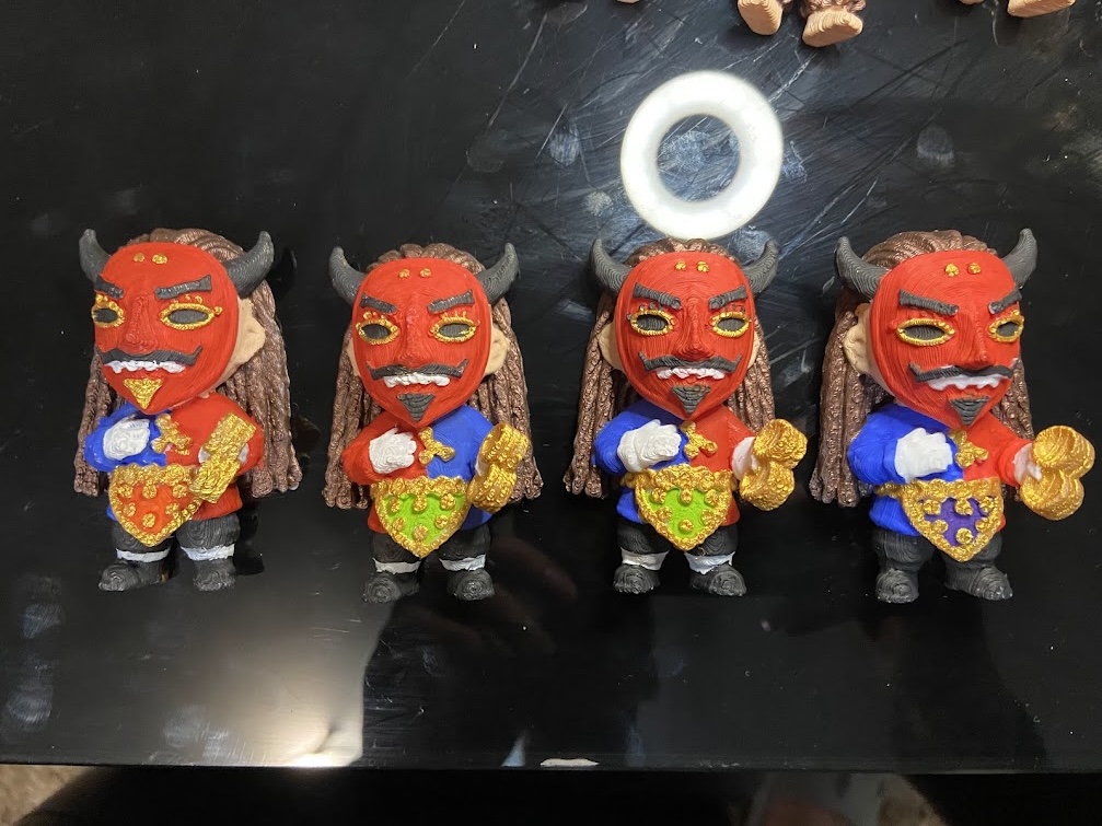 Los cuatro imanes de Diablo de lata alineados sobre la mesa del taller