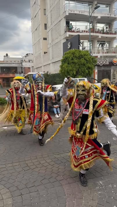 Grupo de Diablos de lata con máscaras doradas y capas de flecos en pleno desfile