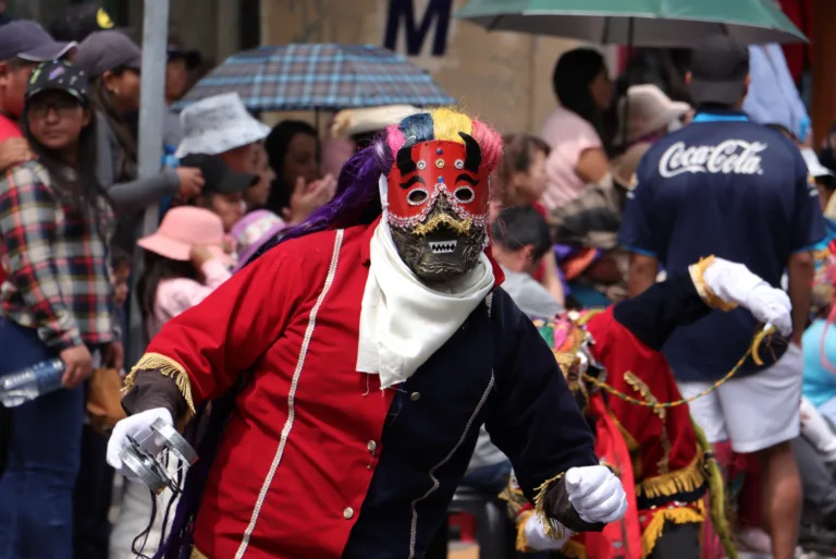 Diablo de lata con máscara roja y melena de colores danzando entre el público